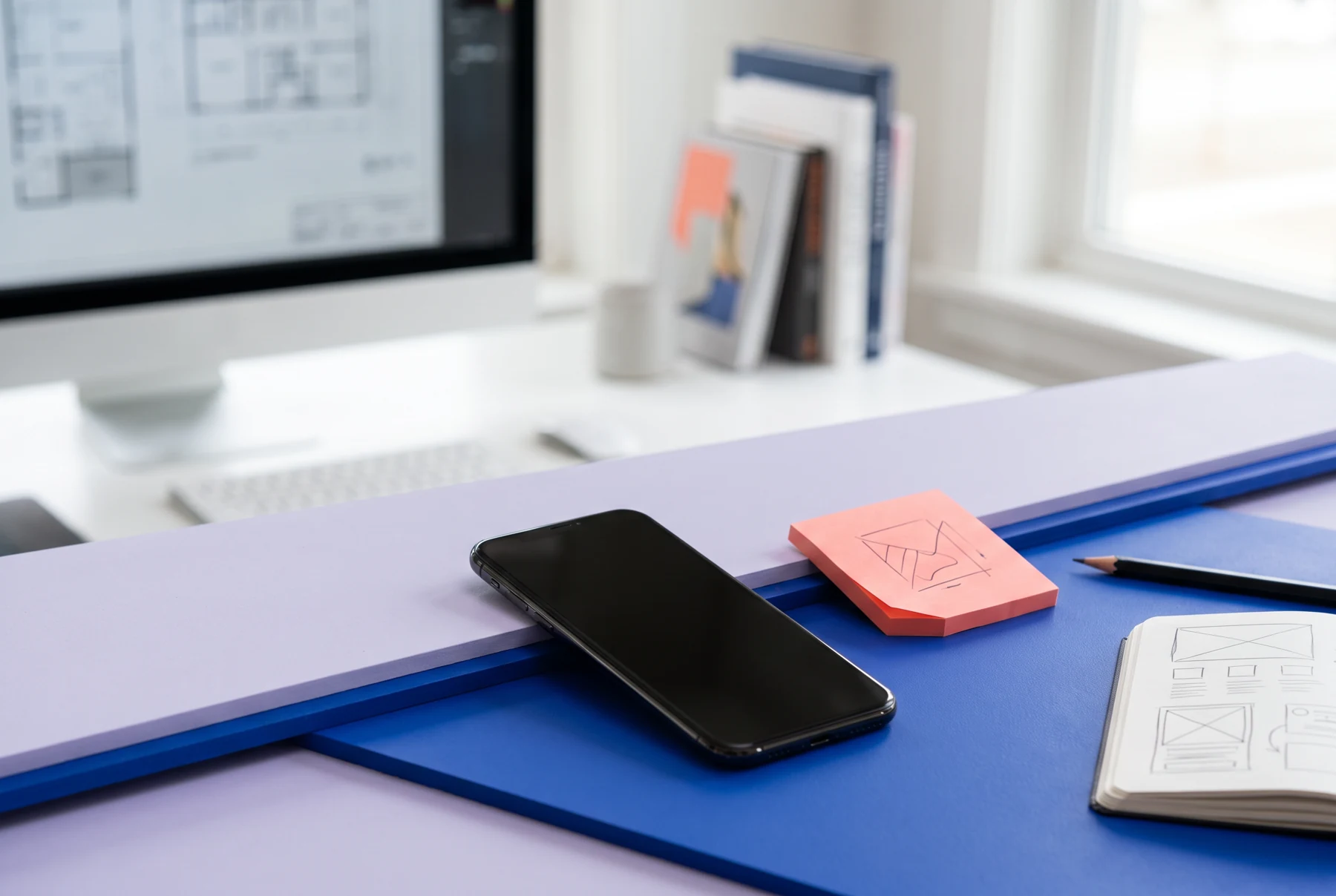 A phone and sketches on a blue work surface