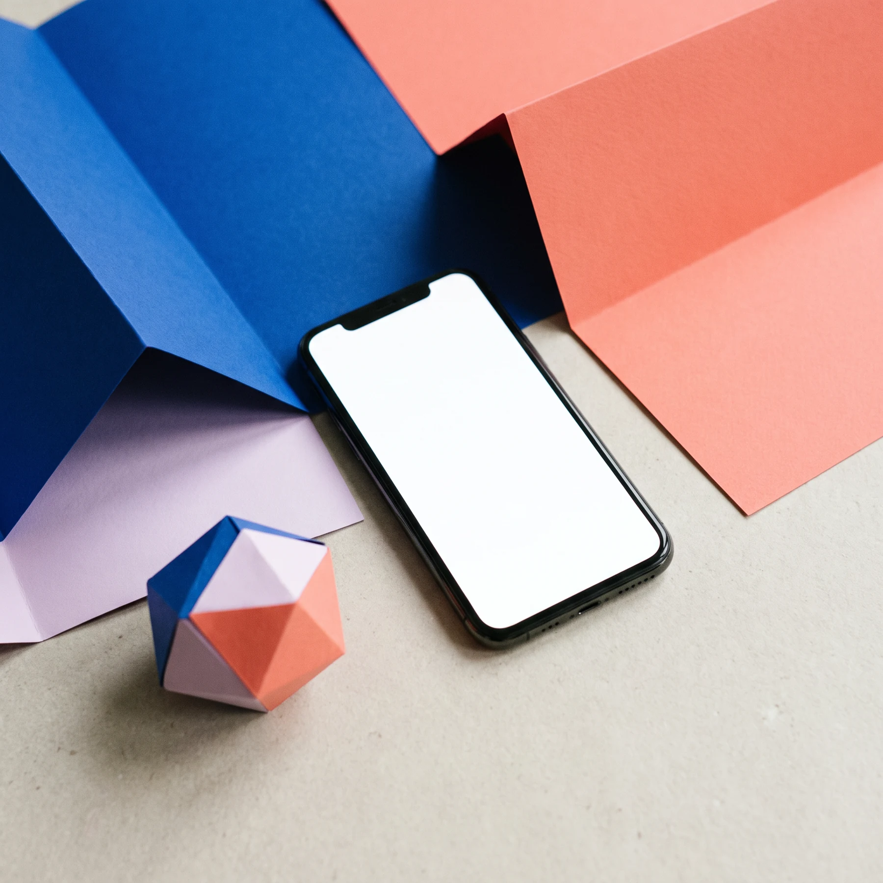 A smartphone on geometric cobalt and coral paper